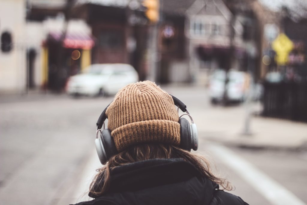 person with headphones on crossing the street