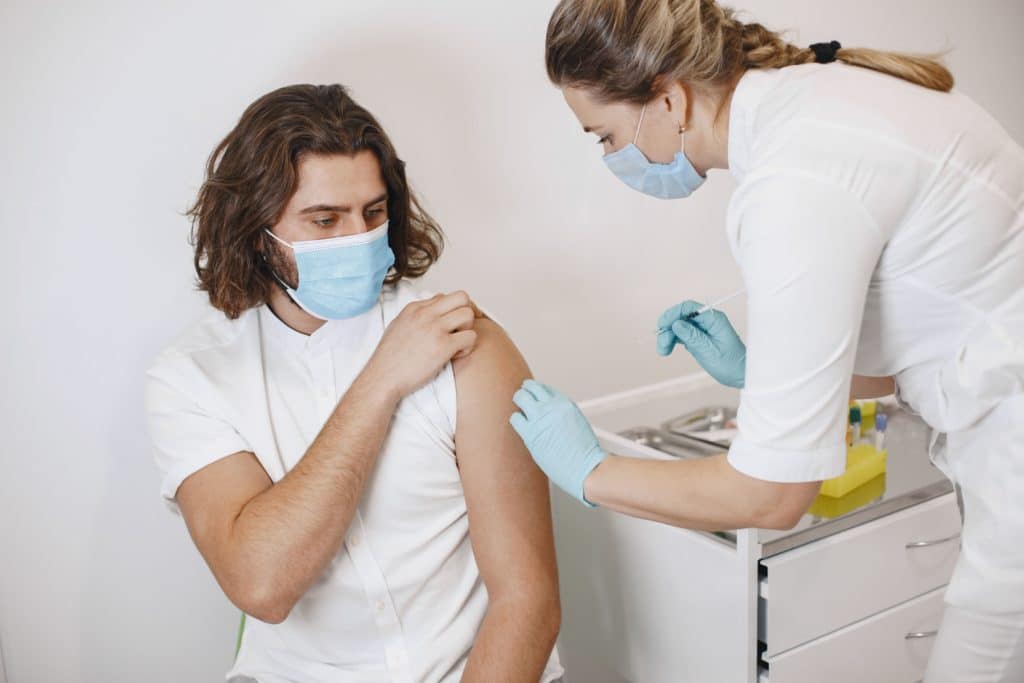 photo of man and a nurse about to administer a vaccination