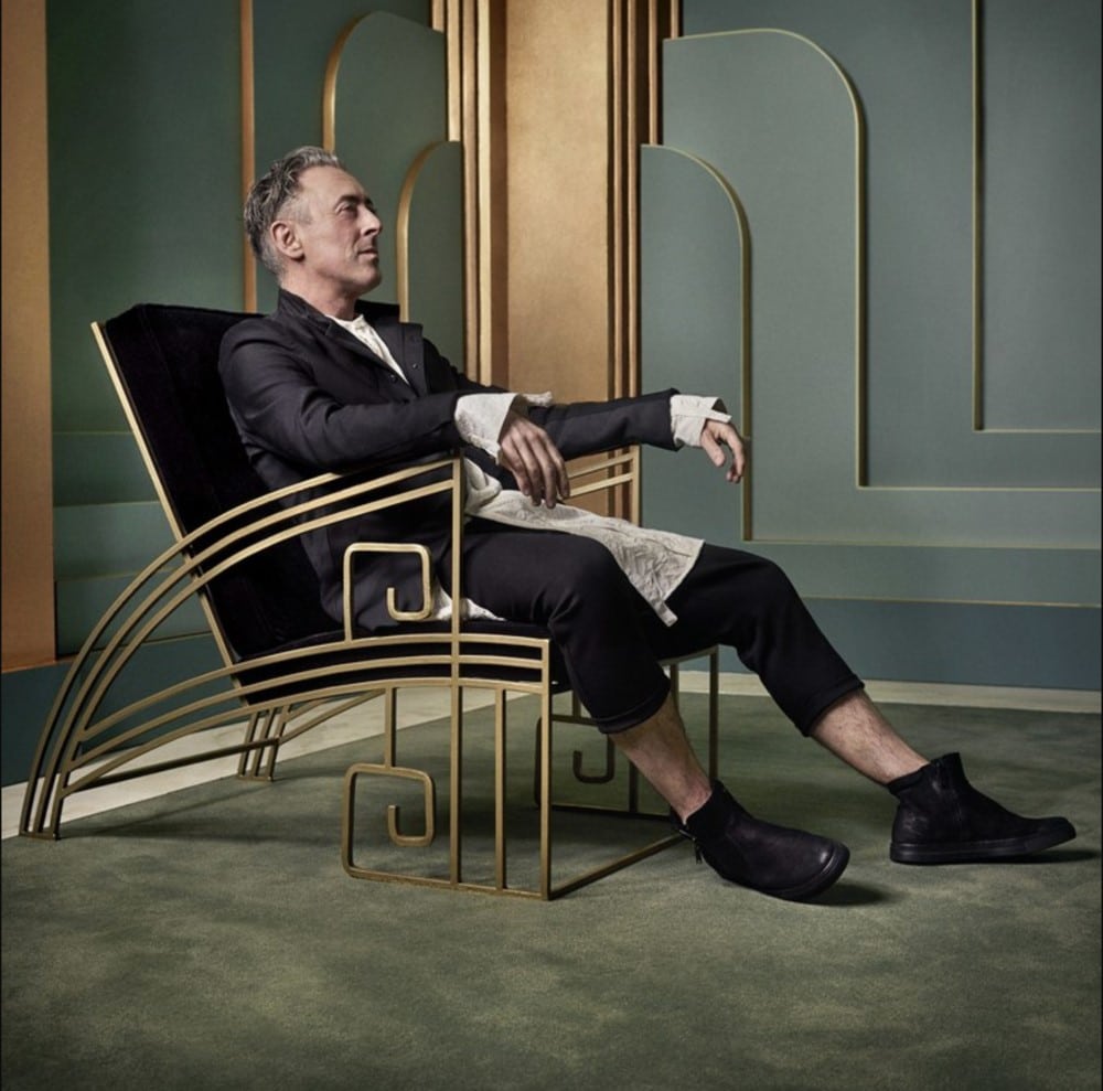 alan-cumming-sitting-in-a-chair-smiling