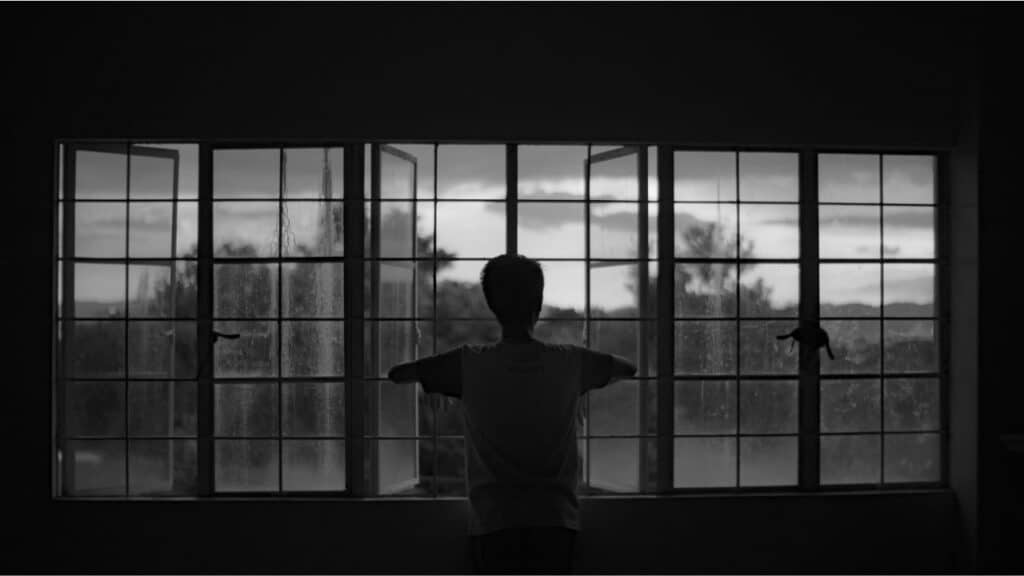 A_lonely_scared_man_looks_out_a_window