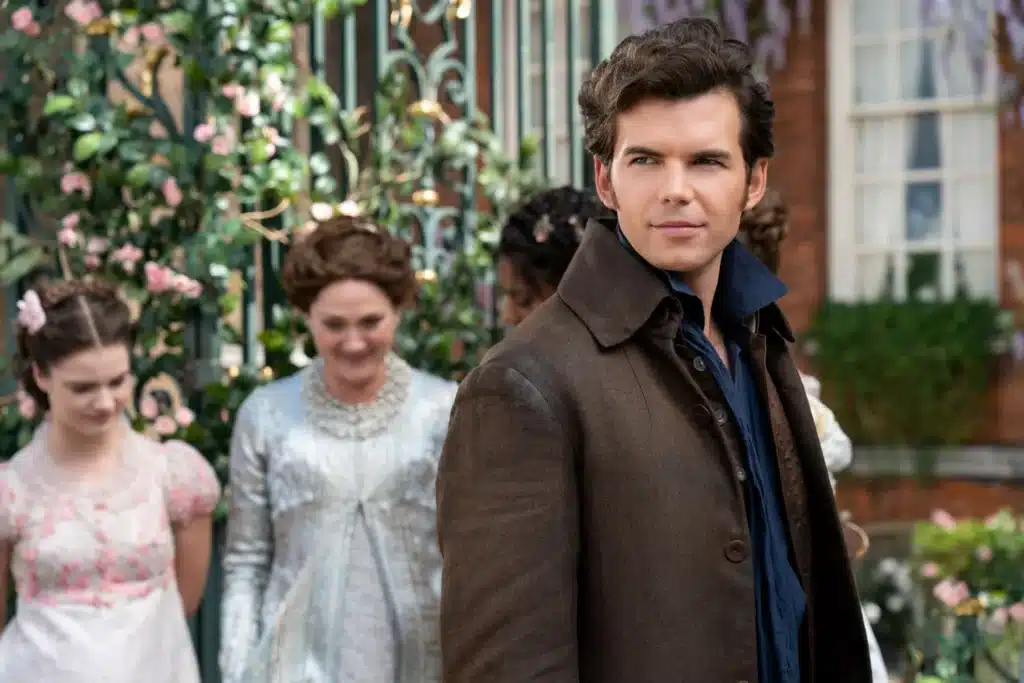 Colin Bridgerton stands in the foreground while his youngest sister, Hyacinth, his mother, the Dowager Viscountess Bridgerton and his sister-in-law, Viscountess Kate Bridgerton in the background.