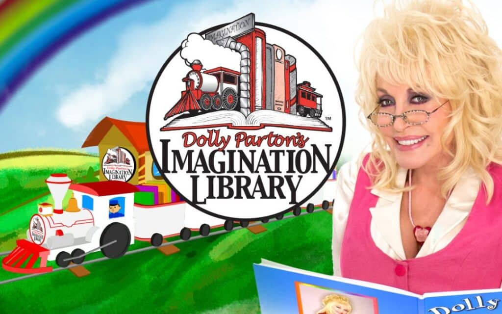 Imagination-Library-Dolly-Parton-holding-a-book-with-a-cartoon-drawing-of-a-train-in-the-background