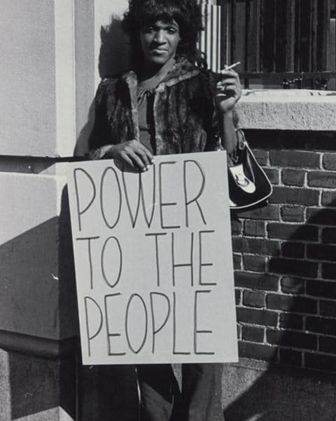 stonewall-great-leaders-black-and-white-photo-of-marsha-p-johnson-holding-a-cigarette-and-a-sign-that-says-power-to-the-people-trans-gay