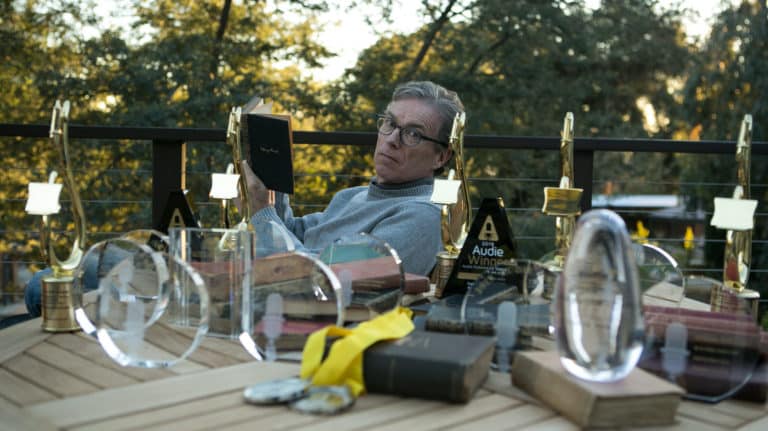 simon-vance-sitting-at-a-table-reading-a-book