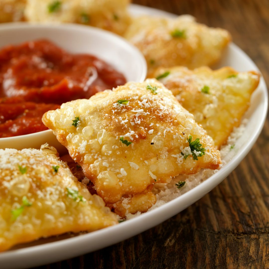 A place of fried ravioli with a small bowl of marinara sauce-food-truck-genre-reading
