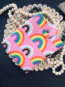 10-tempting-gifts-queer-book-nerds-will-love-pink-cover-with-rainbows-over-a-knit-circle-background