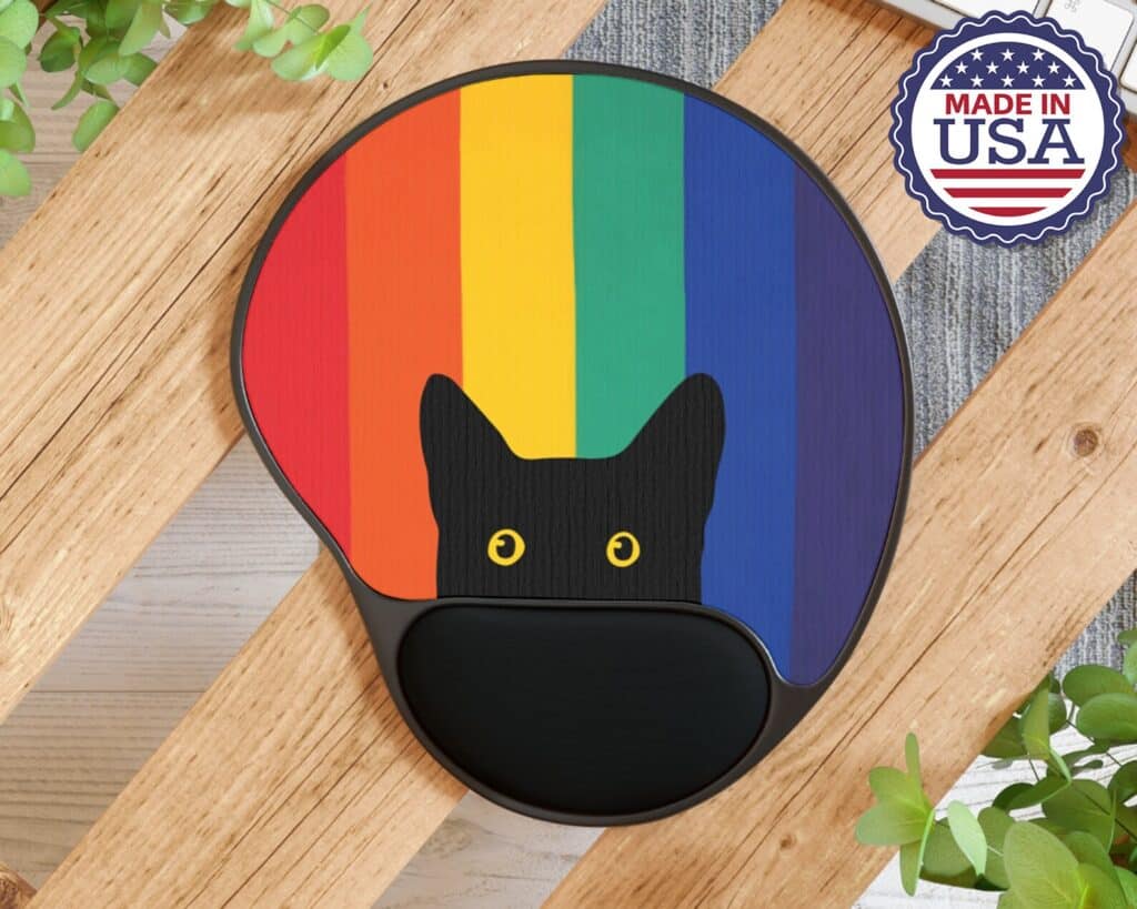 5-inexpensive-gifts-to-surprise-your-favorite-queer-writer-mousepad-with-black-cushion-and-black-cat-peeking-up-over-rainbow-background-photographed-on-a-wooden-bench