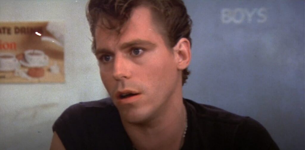 teenage-boy-black-tee-shirt-in-conversation-mouth-slightly-open-grease