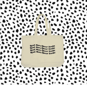 10-tempting-gifts-queer-book-nerds-will-love-white-tote-bag-with-read-more-queer-books-written-three-times-in-wavy-font-over-a-spotted-white-background