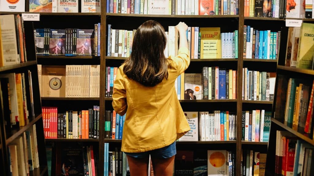 girl-reaching-for-books-on-shelf
