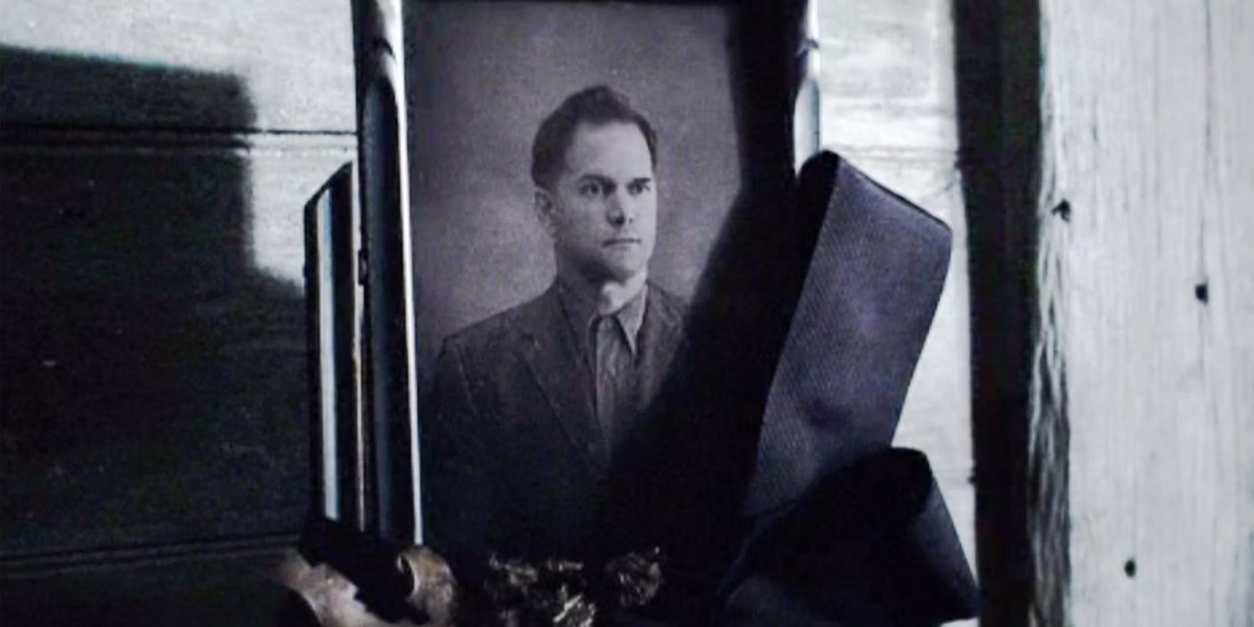 A black and white framed photograph of a man in a suit staring (Katniss' father).